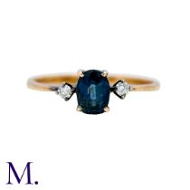 A Sapphire And Diamond Ring in 14k yellow gold, set with an oval cut sapphire between two round