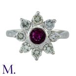 A Ruby And Diamond Cluster Ring in 18k white gold, set with a central round cur ruby within a border