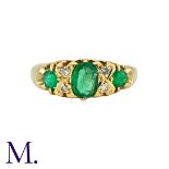 An Emerald And Diamond Ring in 18k yellow gold, set with a principal oval cut emerald, and two round