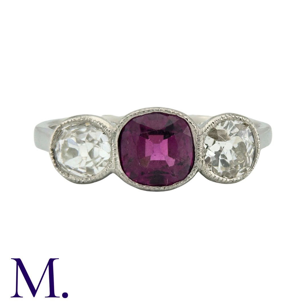 A Ruby And Diamond Three Stone Ring in platinum, set with a principal cushion cut ruby of