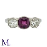 A Ruby And Diamond Three Stone Ring in platinum, set with a principal cushion cut ruby of