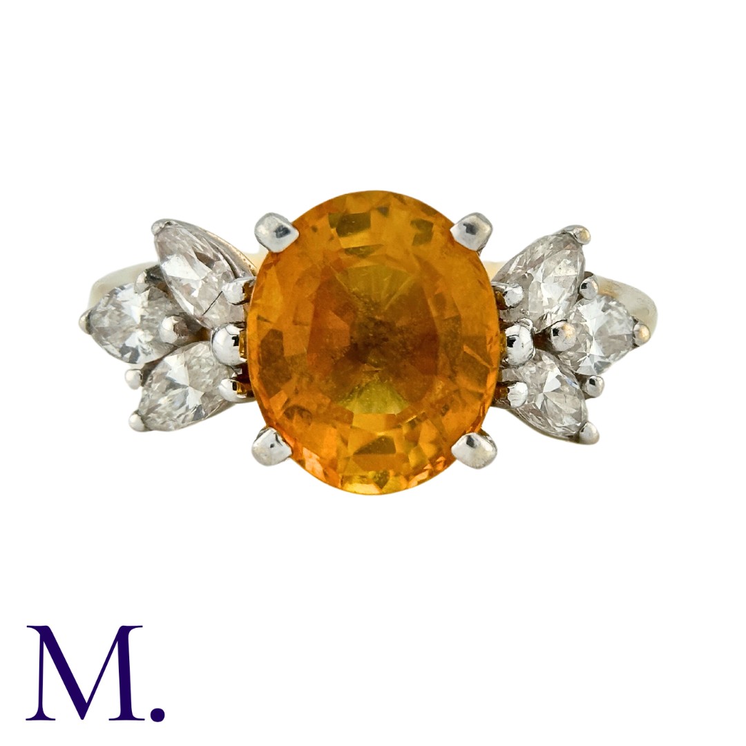 A Sapphire and Diamond Ring in 14K yellow gold, set with an oval cut yellow-orange sapphire of