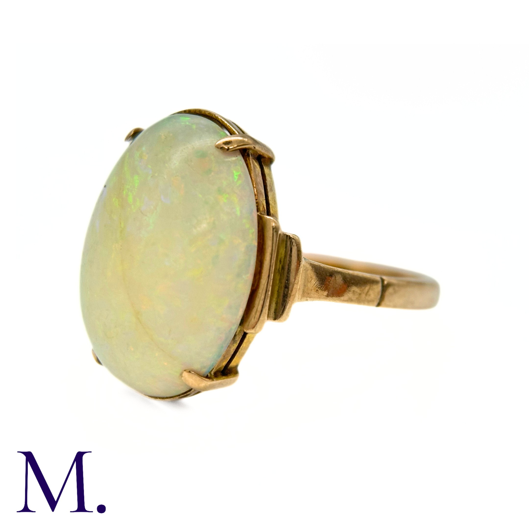 An Opal Ring in 9k yellow gold, set with a cabochon opal to stepped shoulders. Stamped 9ct. Size: