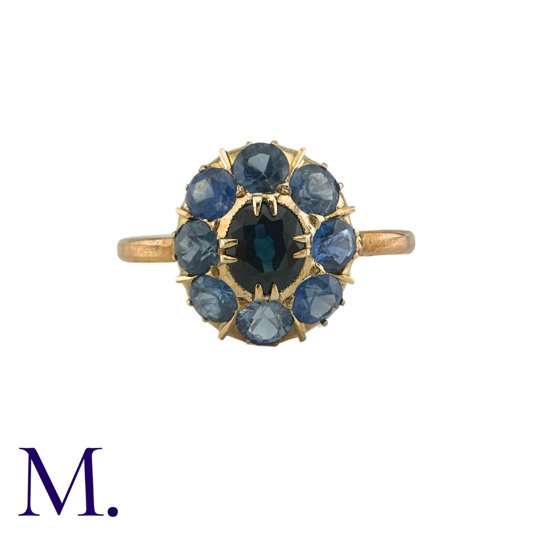 A Sapphire Cluster Ring in yellow gold, comprising a cluster of round cut sapphires surrounding a