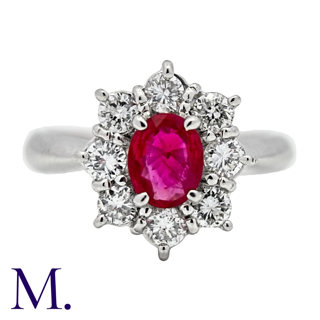 A Ruby & Diamond Cluster Ring in platinum, set with an oval cut ruby of approximately 0.65ct and