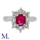 A Ruby & Diamond Cluster Ring in platinum, set with an oval cut ruby of approximately 0.65ct and