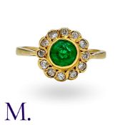 An Emerald and Diamond Cluster Ring in 18K yellow gold, set with a round cut emerald to the centre