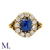 A Sapphire And Diamond Cluster Ring in 18k yellow gold, set with a principal cushion cut sapphire of