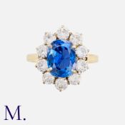 A Burma Sapphire & Diamond Cluster Ring in 18K gold. Oval cut sapphire weighing 3.84ct accompanied