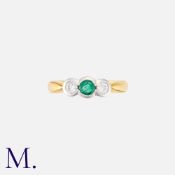 An Emerald And Diamond Three Stone Ring in 18k gold, set with a central emerald, flanked either side