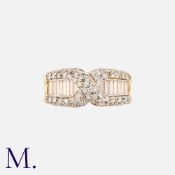 A Diamond Ring in 18k yellow gold, of crossover design, set with round cut diamonds and baguette cut