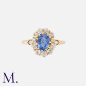 A Sapphire And Diamond Cluster Ring in yellow gold, set with a principal oval cut sapphire of