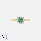 An Emerald and Diamond Cluster Ring in 18K yellow gold, set with a round cut emerald to the centre
