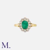 An Emerald and Diamond Cluster Ring in 18K yellow and white gold set with an oval cut emerald to the