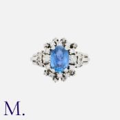 A Sapphire and Diamond Cluster Ring in 18K white gold set with an oval-cut sapphire of good colour