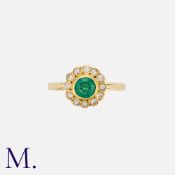 An Emerald and Diamond Cluster Ring in 18K yellow gold, bezel set with a round cut emerald with