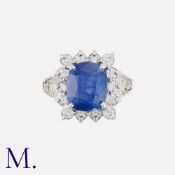 A Sapphire And Diamond Cluster Ring in 18k white gold, set with a principal cushion cut sapphire