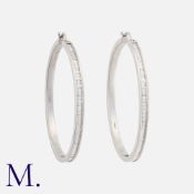 A Pair of Large Diamond Hoop Earrings in 18K white gold set with baguette cut diamonds weighing