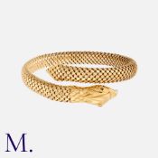A Snake Bangle in 18k yellow gold, designed as a coiled snake with textured articulated scales.