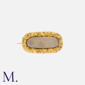 A Georgian Locket Brooch in yellow gold, set centrally with a glass locket front containing woven