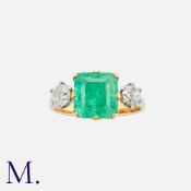 An Emerald And Diamond Three Stone Ring in yellow gold, set with a central octagonal cut emerald