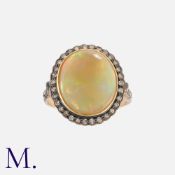 An Opal And Diamond Cluster Ring in silver and 14k white gold, set with a cabochon opal within a