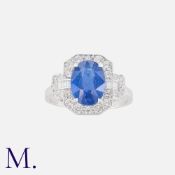 A Sapphire And Diamond Cluster Ring in 18k white gold, set with a central oval cut sapphire of