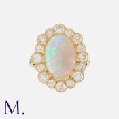 An Opal And Diamond Cluster Ring in 18k yellow gold, set with a principal cabochon opal of