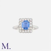 A Sapphire And Diamond Cluster Ring in platinum, set with a rectangular step cut sapphire of