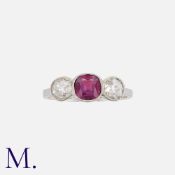 A Ruby And Diamond Three Stone Ring in platinum, set with a principal cushion cut ruby of