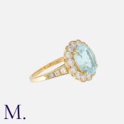An Aquamarine And Diamond Cluster Ring in yellow gold, set with a central oval cut aquamarine of