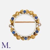 An Antique Enamel, Pearl And Sapphire Wreath Brooch in 15k yellow gold, comprising a white enamelled