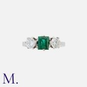 An Emerald And Diamond Three Stone Ring in 18k white gold, set centrally with a step cut emerald
