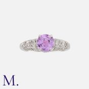 A Pink Sapphire and Diamond Ring in platinum, set to the centre with a round cut sapphire weighing