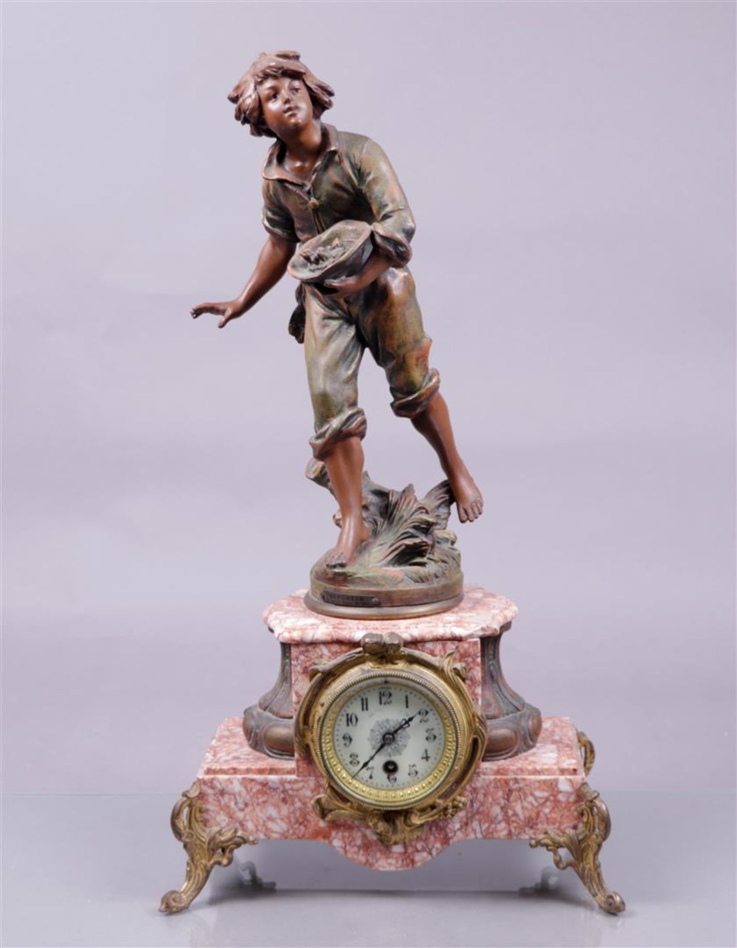 A mantel clock with clock statue 'Le Denicheur' after Franciscus Moreau, on a pink marble base. Fran