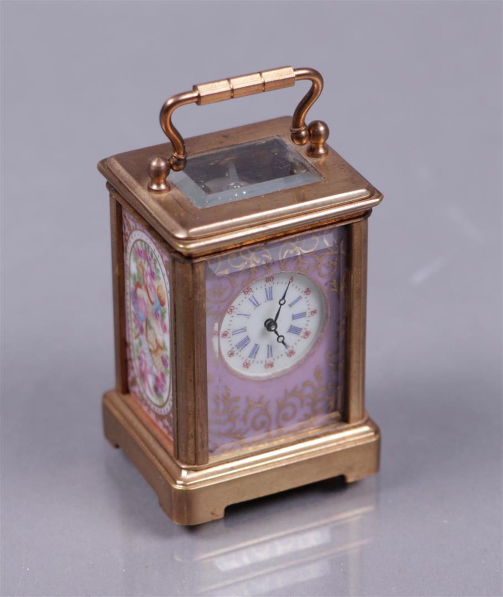 A brass travel alarm clock with polychrome decorated plaques, 20th century.
H.: 5,5 cm.