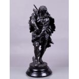 A dark patinated metal statue on a wooden base of a hunter storing a bird in a hunting bag. 19th cen