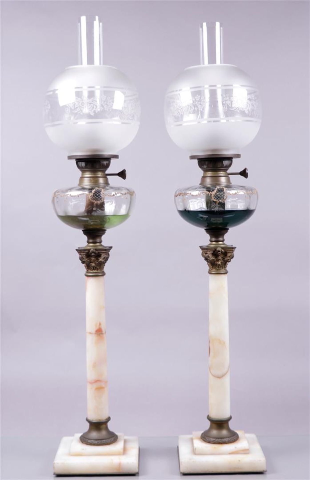 A pair of 19th century cold-painted oil lamps on white marble columns with Corinthian bronze capital