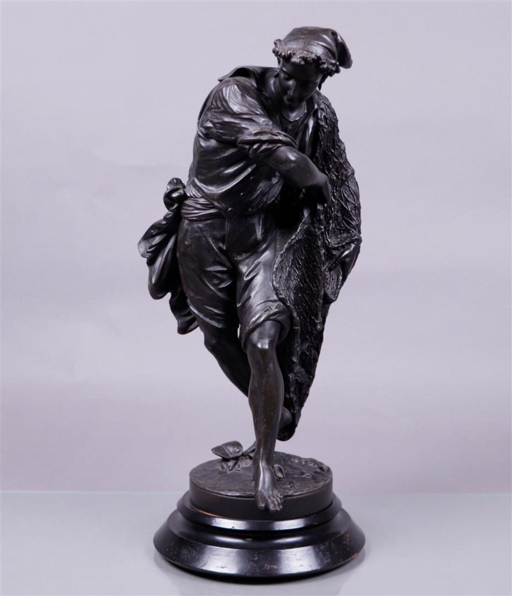 A darkly patinated metal statue on a wooden base of a Neapolitan fisherman casting his net. 19th cen