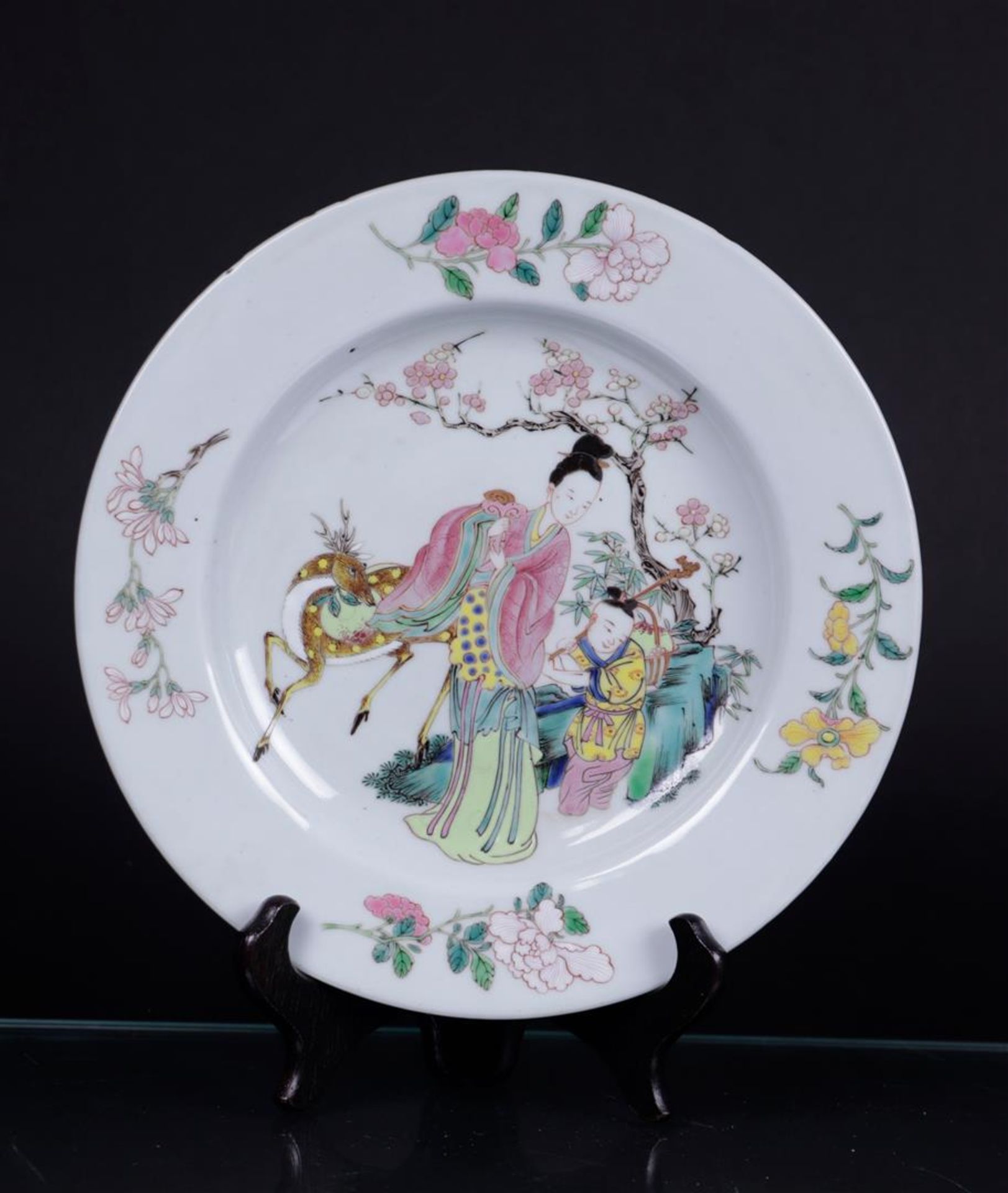 A porcelain Famille rose plate decorated with two figures and a ruby red ground on the back. China, 