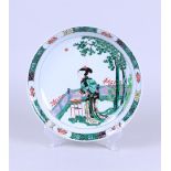A porcelain Famille Verte dish with a standing long table near a pavilion with a pine tree. Marked o