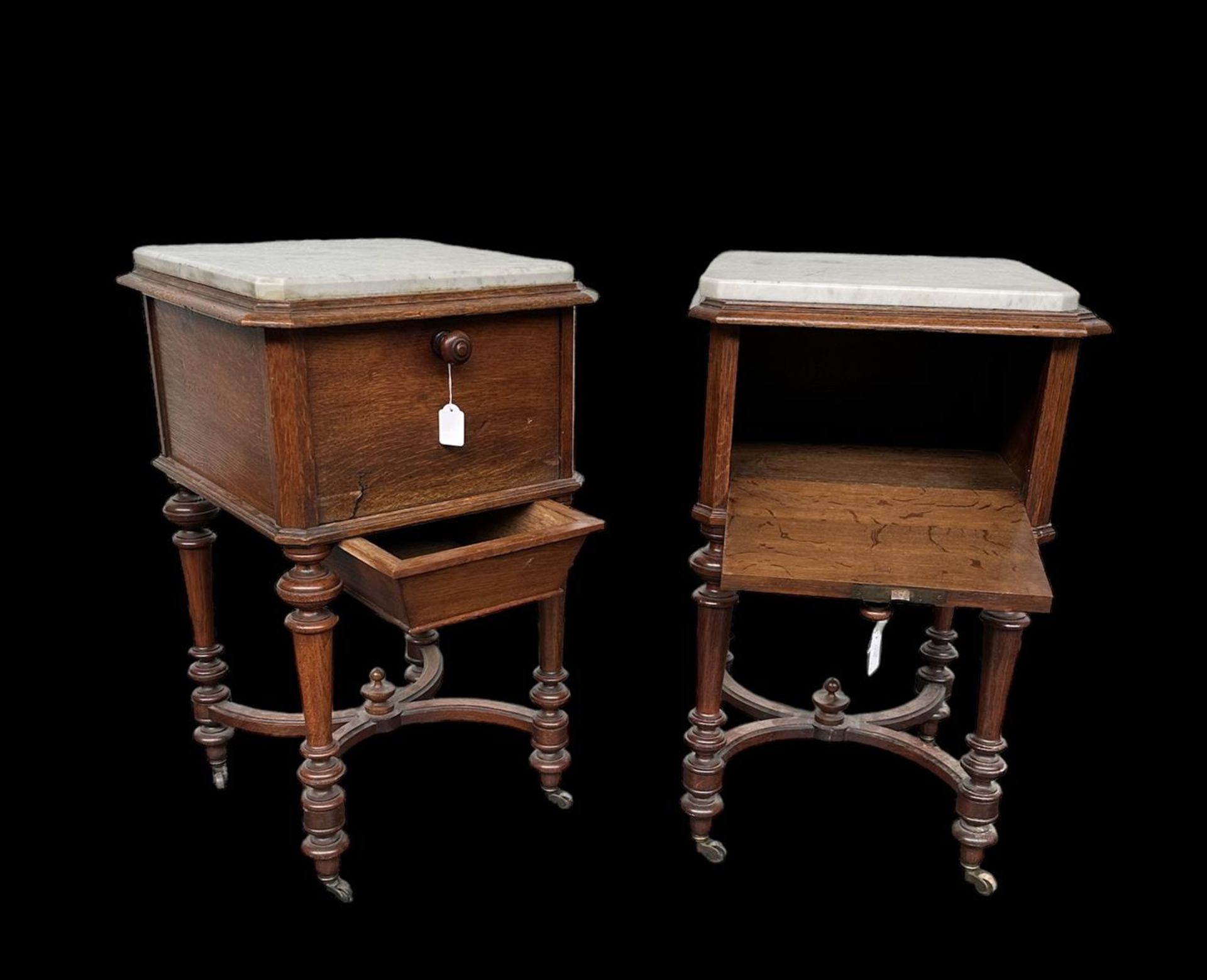 A pair of oak bedside tables or potty cupboards on turned legs with bronze wheels. Both have a drawe