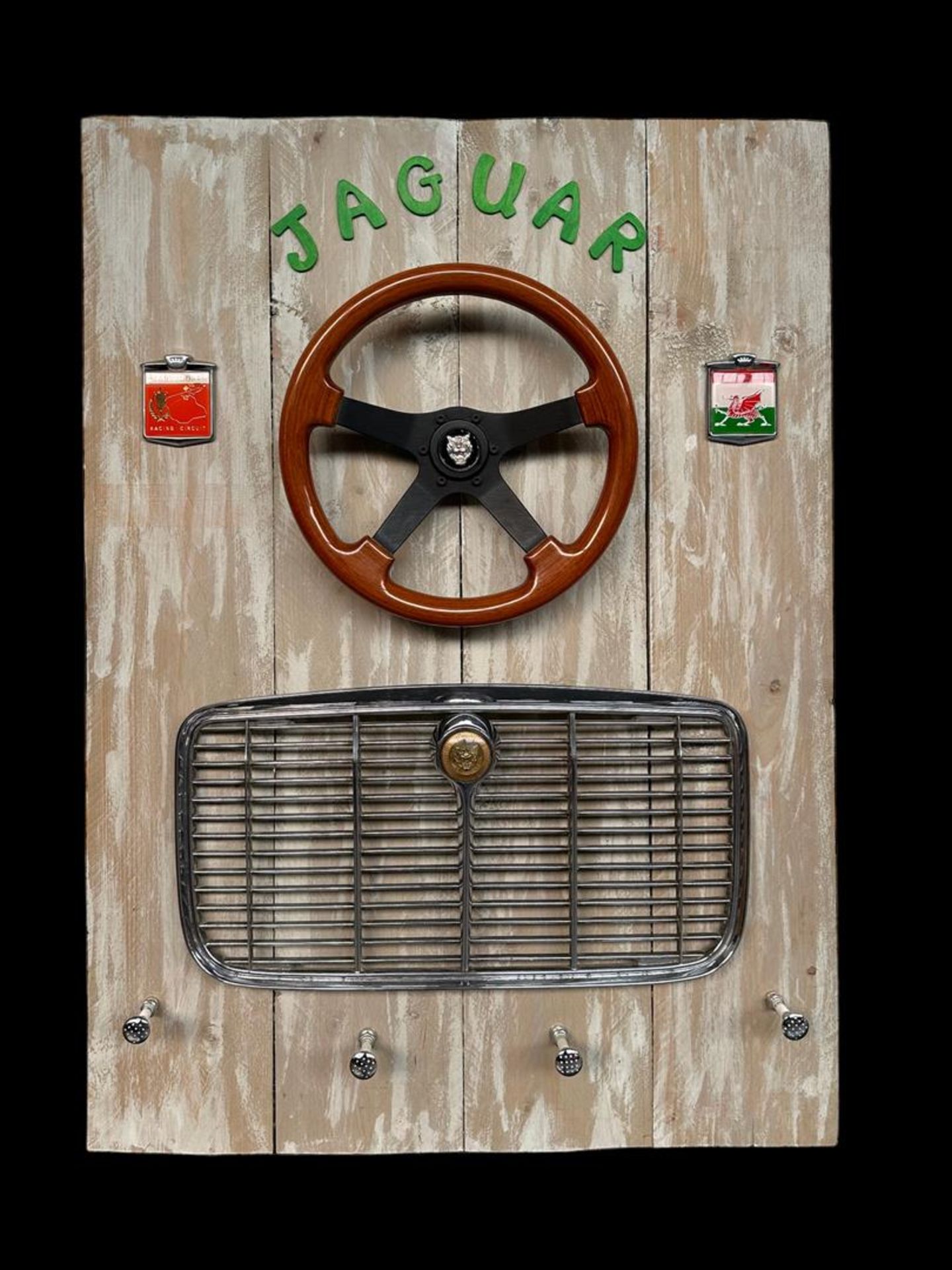 A coat rack made from Jaguar parts including steering wheel and grille, along with two emblems inclu