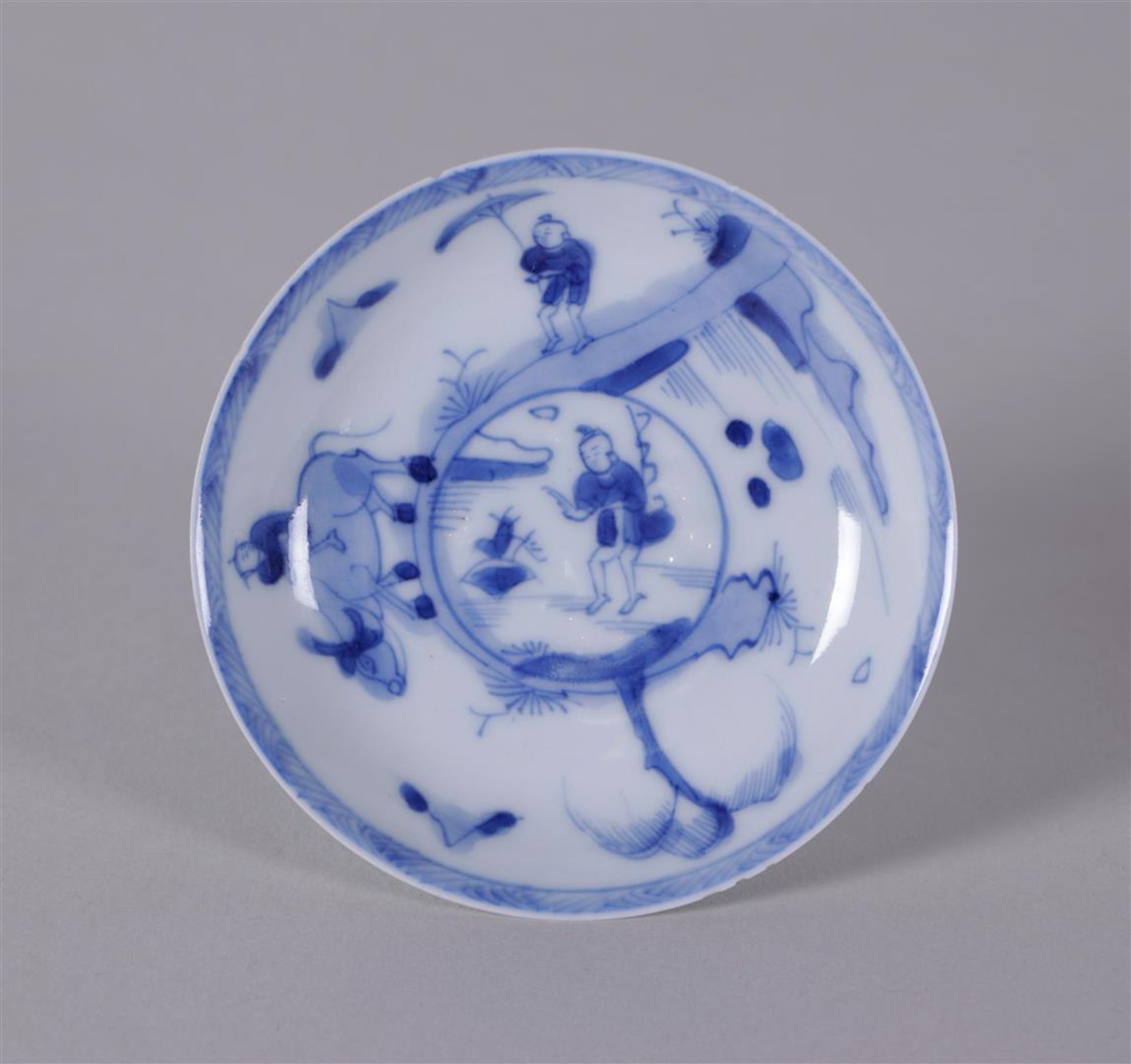 A small blue and white porcelain saucer with a boy on water buffalo decor. China, Kangxi ca 1722.
Di