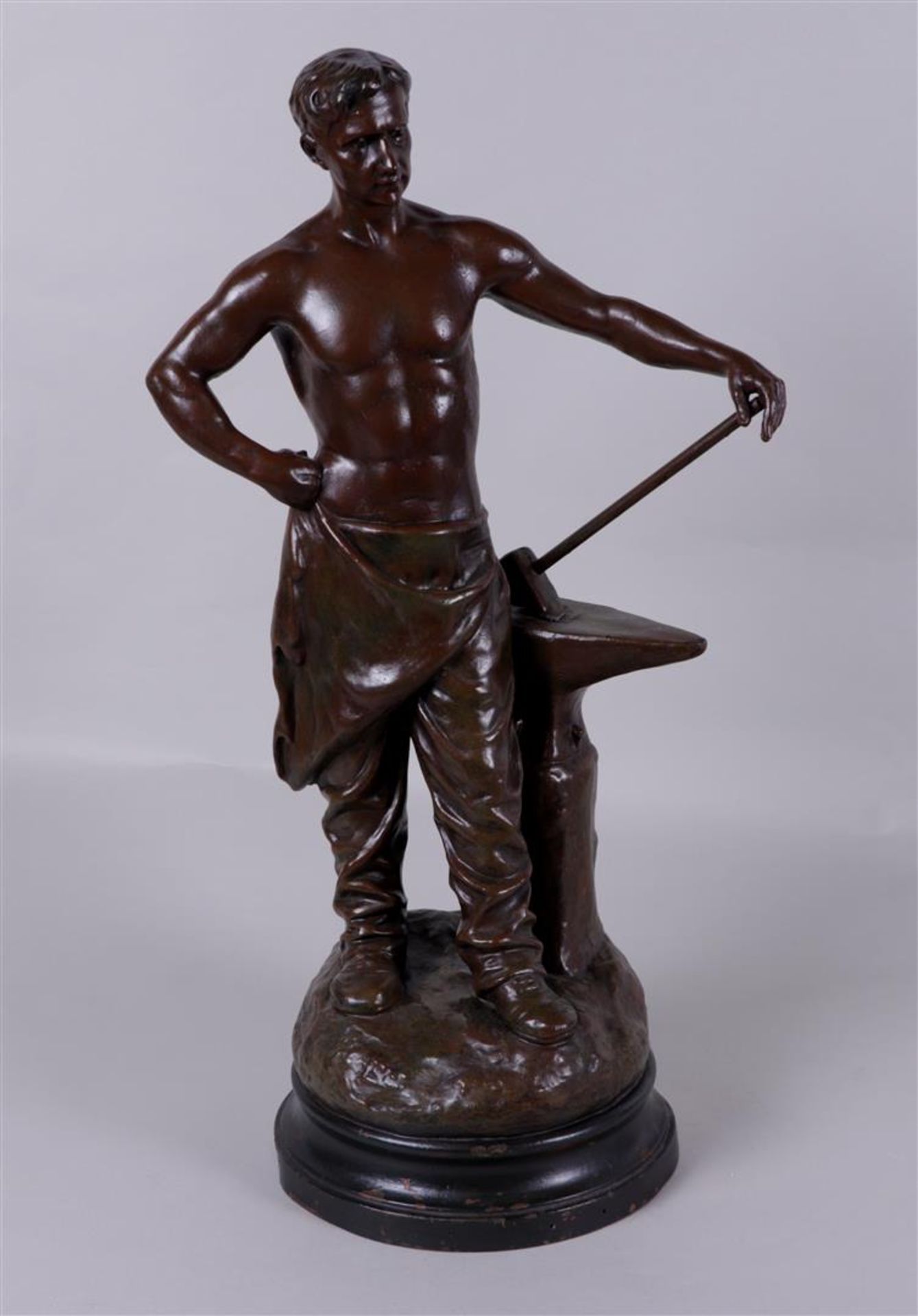 Géo Maxim (1885 - 1940), A cast statue of a blacksmith. on wooden base, signed (in the foot), ca. 19