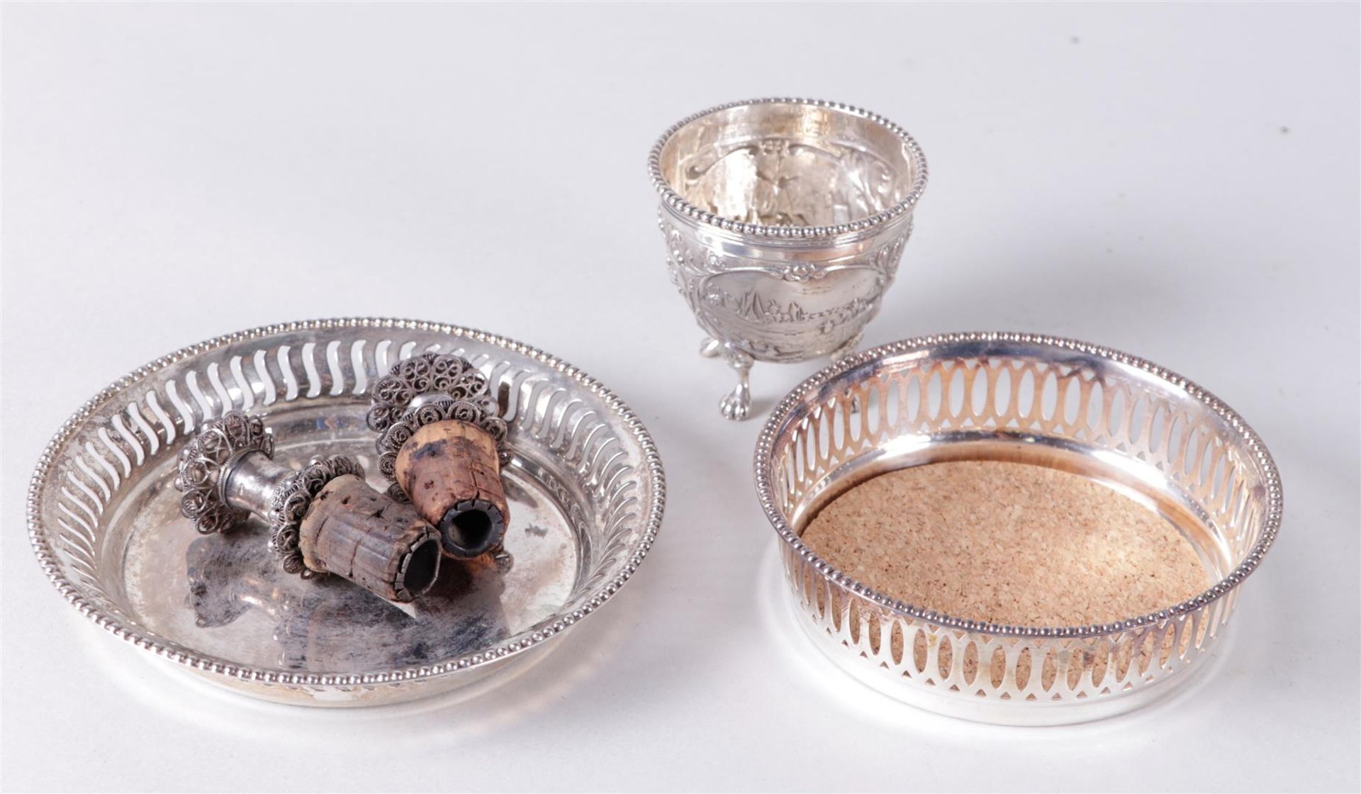 A lot with two base bottle trays and two silver filigree bottle stoppers.