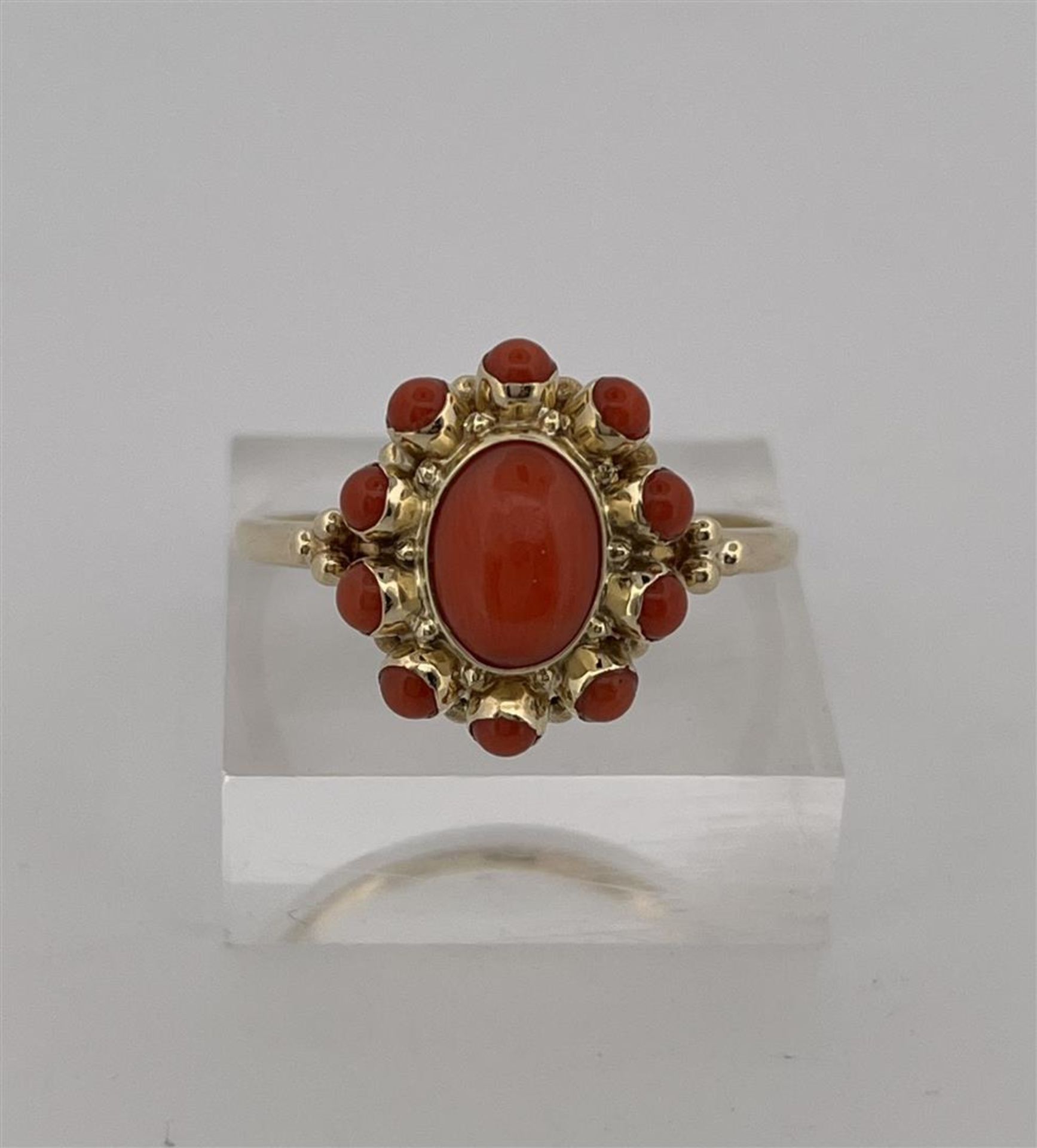 14kt yellow gold rosette ring set with red coral.
The ring is set with 1 central oval cabochon cut r