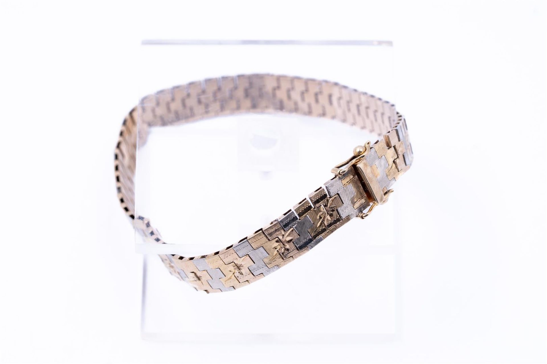 14kt bicolor gold bracelet. The bracelet has a beautiful decoration at the top of a flower motif. Th