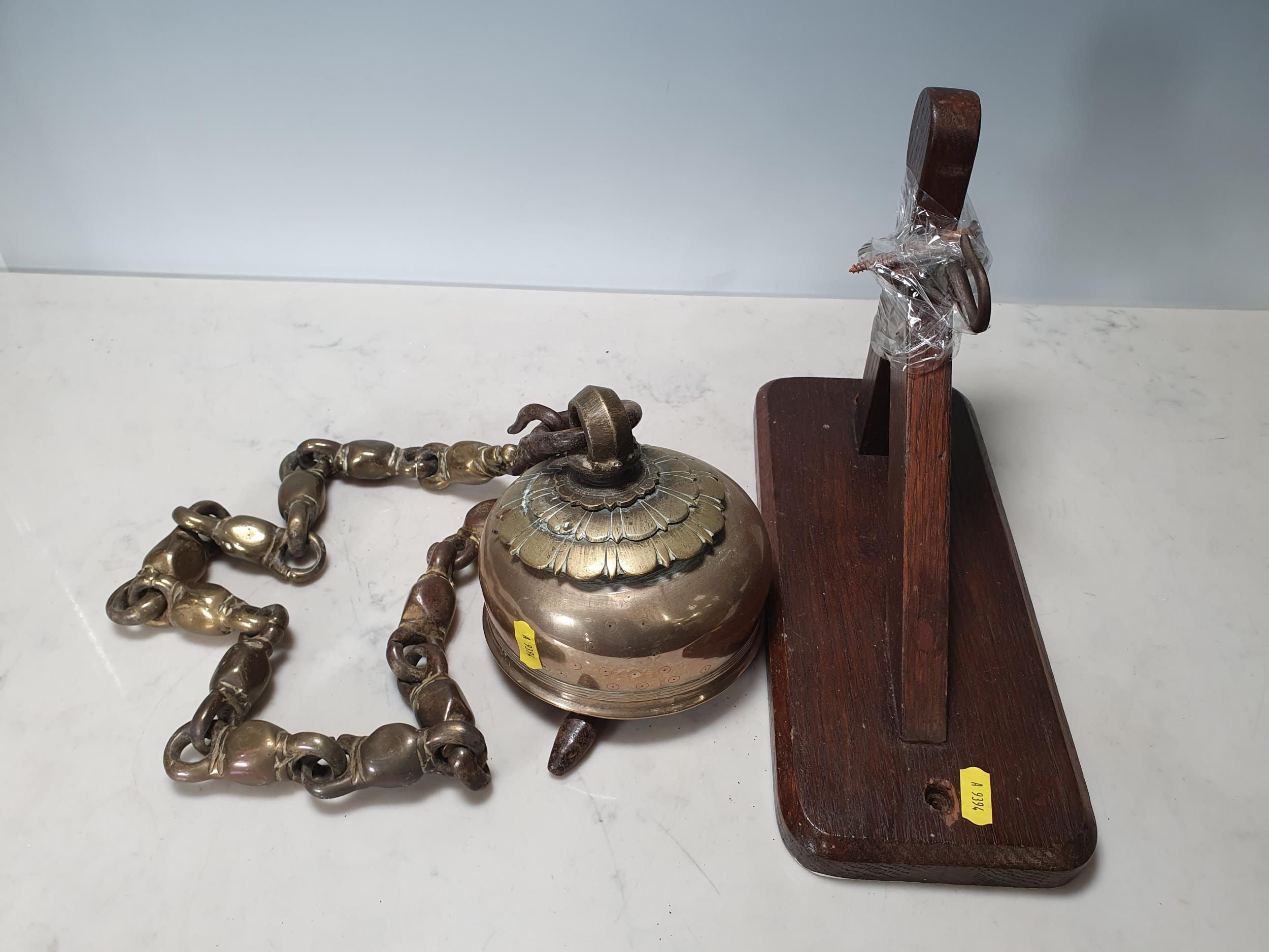 A Sino Tibetan Brass Bell, mounted on a brass chain and an oak Wall Bracket