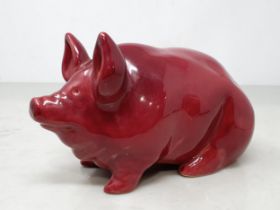 A Seated Pottery Pig in Burgundy/Red glaze, "bearing marks to underside," 4"High x 7"Long.